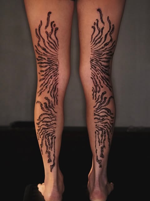 Mirrored organic tattoo marks on the backs of both legs
